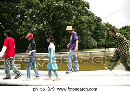 Side profile of three young men with two young women walking along a pond View Large Photo Image Stock Photo - Side profile of three young men with two young women walking along a pond. Fotosearch