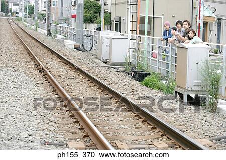 Stock Image - Three young men and two young women leaning against a railing. Fotosearch
