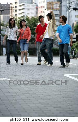 Stock Image - Three young men and two young women walking. Fotosearch