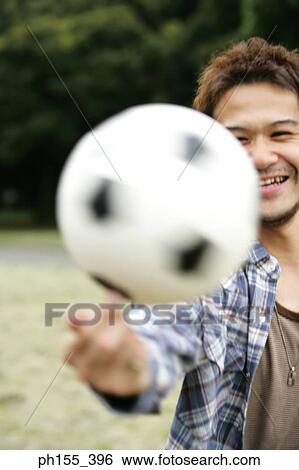 Stock Photograph - Young man spinning a soccer ball on his finger. Fotosearch
