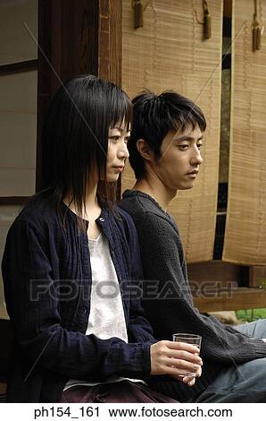 Close-up of a young couple sitting View Large Photo Image Stock Image - Close-up of a young couple sitting. Fotosearch