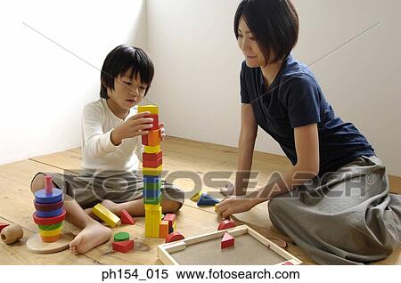 Stock Photography - Girl playing with blocks with her mother looking at her. Fotosearch