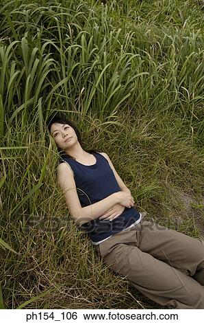 High angle view of a young woman lying on the grass View Large Photo Image Stock Photograph - High angle view of a young woman lying on the grass. Fotosearch
