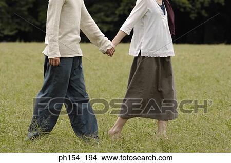 Low section view of a man holding a woman's hand View Large Photo Image Picture - Low section view of a man holding a woman's hand. Fotosearch