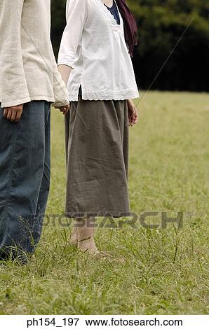 Stock Photo - Low section view of a man holding a woman's hand. Fotosearch
