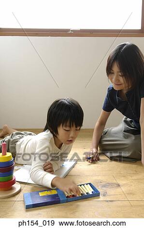 Stock Photo - Mid adult woman and her daughter coloring in a coloring book. Fotosearch