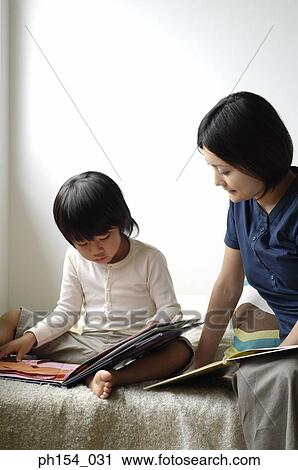 Stock Image - Mid adult woman teaching her daughter. Fotosearch