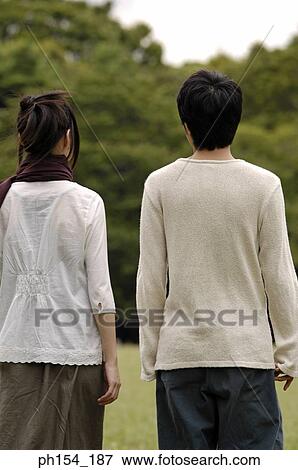 Rear view of a young couple standing together View Large Photo Image Stock Photo - Rear view of a young couple standing together. Fotosearch