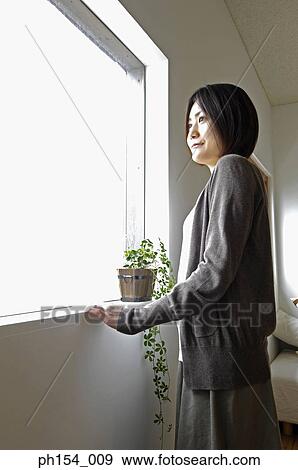 Side profile of a young woman looking through a window View Large Photo Image Stock Photo - Side profile of a young woman looking through a window. Fotosearch