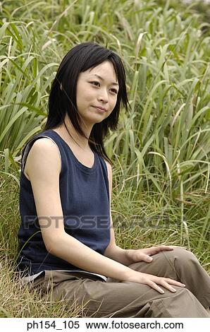 Side profile of a young woman sitting on the grass View Large Photo Image Stock Photography - Side profile of a young woman sitting on the grass. Fotosearch