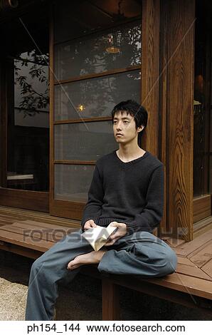 Young man holding a book and thinking View Large Photo Image Picture - Young man holding a book and thinking. Fotosearch