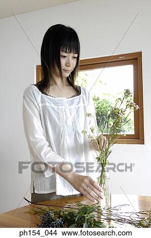 Young woman arranging a flower vase View Large Photo Image Picture - Young woman arranging a flower vase. Fotosearch