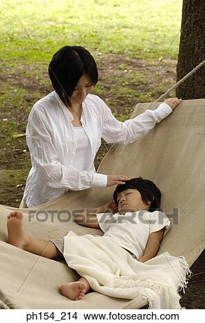 Young woman standing beside her daughter sleeping in a hammock View Large Photo Image Picture - Young woman standing beside her daughter sleeping in a hammock. Fotosearch