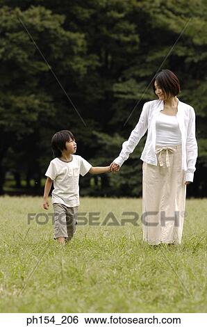 Young woman walking with her daughter on the grass View Large Photo Image Stock Photograph - Young woman walking with her daughter on the grass. Fotosearch