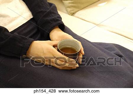 Mid section view of a woman holding a cup of black tea View Large Photo Image Stock Photo - Mid section view of a woman holding a cup of black tea. Fotosearch