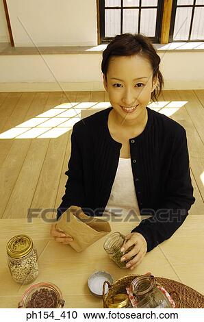 Portrait of a young woman filling a jar with beans and smiling View Large Photo Image Stock Image - Portrait of a young woman filling a jar with beans and smiling. Fotosearch