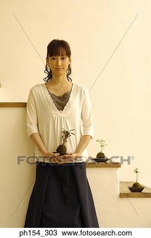Portrait of a young woman holding a potted plant View Large Photo Image Stock Image - Portrait of a young woman holding a potted plant. Fotosearch