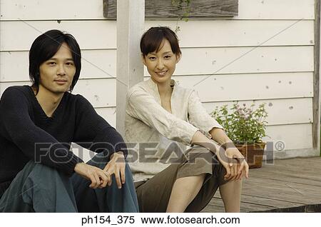 Portrait of a young woman sitting with a young man and smiling View Large Photo Image Stock Photography - Portrait of a young woman sitting with a young man and smiling. Fotosearch