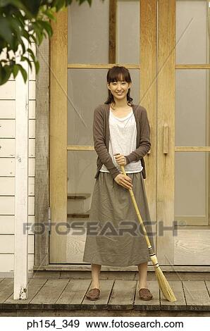 Portrait of a young woman standing and holding a broom View Large Photo Image Stock Photo - Portrait of a young woman standing and holding a broom. Fotosearch