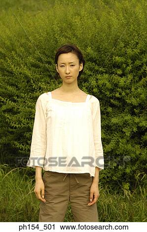 Portrait of a young woman standing in a field View Large Photo Image Stock Image - Portrait of a young woman standing in a field. Fotosearch