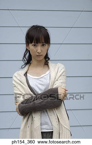 Stock Image - Portrait of a young woman standing with her arms crossed. Fotosearch