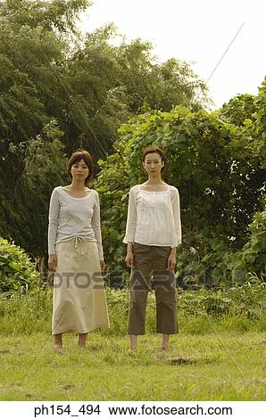 Portrait of two young women standing in a field View Large Photo Image Picture - Portrait of two young women standing in a field. Fotosearch