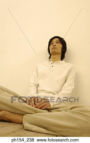 Stock Photo - Young man sitting on the floor with his legs crossed. Fotosearch