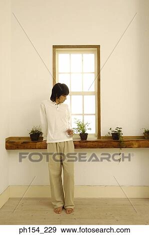Young man standing in front of a window with a glass View Large Photo Image Stock Photo - Young man standing in front of a window with a glass. Fotosearch