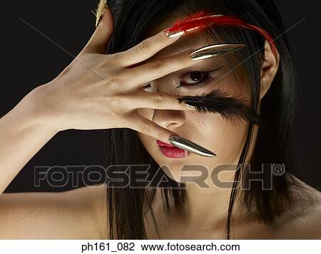 Woman with a fang and feathers on finger nails, face covered by one hand View Large Photo Image Stock Image - Woman with a fang and feathers on finger nails, face covered by one hand. Fotosearch