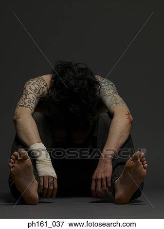 Stock Photo - Young man sitting on floor, with head down. Fotosearch