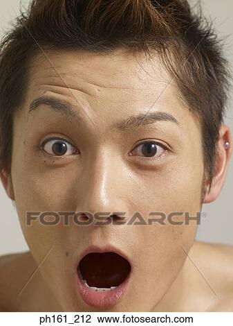 Stock Image - Young man with mouth open wide, close-up. Fotosearch