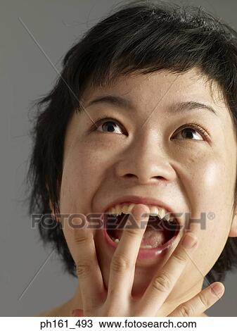 Close-up of woman with hand to her mouth View Large Photo Image Stock Image - Close-up of woman with hand to her mouth. Fotosearch