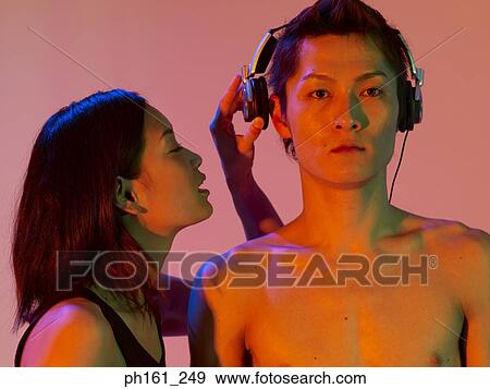 Woman speaking to a man's ears wearing headphones View Large Photo Image Stock Photo - Woman speaking to a man's ears wearing headphones. Fotosearch