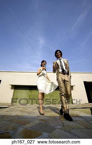 A couple carrying cocktails, outdoors View Large Photo Image Stock Photo - A couple carrying cocktails, outdoors. Fotosearch