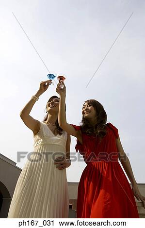 Stock Image - Two women raising a toast, low angle. Fotosearch