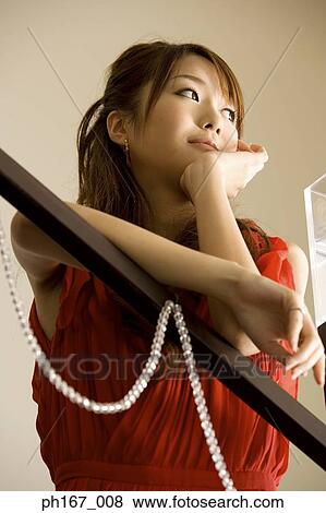 Stock Photo - Woman leaning on banister, looking away, low angle. Fotosearch