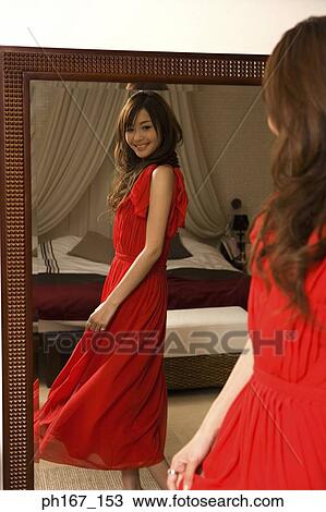 Young woman adjusting dress in front of mirror View Large Photo Image Stock Image - Young woman adjusting dress in front of mirror. Fotosearch