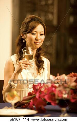 Young woman holding a wine glass at dining table View Large Photo Image Picture - Young woman holding a wine glass at dining table. Fotosearch