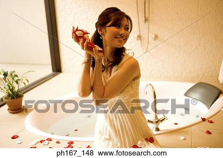 Young woman sitting by bath tub with rose petals in hands View Large Photo Image Stock Photo - Young woman sitting by bath tub with rose petals in hands. Fotosearch