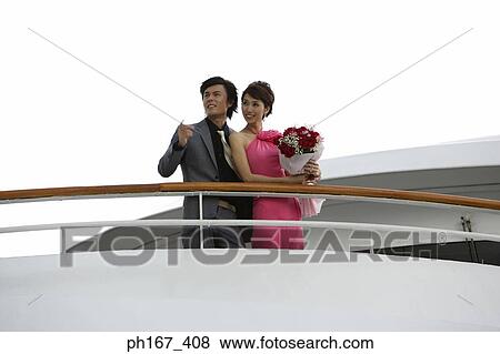 Stock Photo - A couple standing by the railing of a cruise ship. Fotosearch