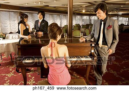 Man watching woman play the piano, with a couple standing by View Large Photo Image Stock Photo - Man watching woman play the piano, with a couple standing by. Fotosearch