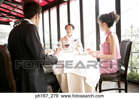 Three people dining in a restaurant View Large Photo Image Stock Photo - Three people dining in a restaurant. Fotosearch