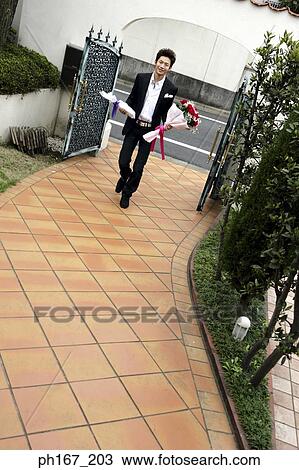 Young man walking through the gate, holding wine and a bouquet of flowers View Large Photo Image Stock Image - Young man walking through the gate, holding wine and a bouquet of flowers. Fotosearch