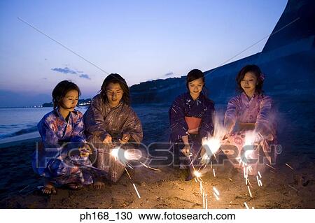 Stock Image - A small group of people with sparklers at the beach. Fotosearch