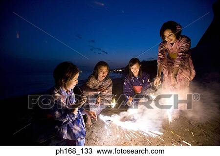 Stock Image - A small group of people with sparklers at the beach. Fotosearch