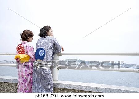 Stock Image - Couple enjoying the view at the pier, rear view. Fotosearch