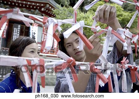 Couple in traditional Japanese clothing tying their fortune slip on a string View Large Photo Image Stock Image - Couple in traditional Japanese clothing tying their fortune slip on a string . Fotosearch