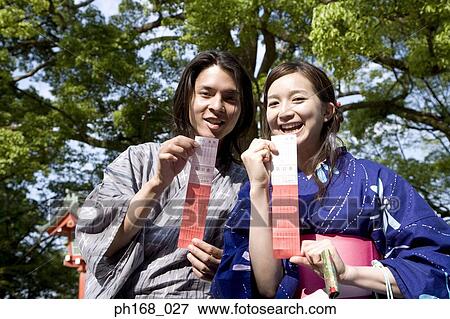 Stock Photo - Couple in traditional Japanese clothing holding up their fortune slips. Fotosearch