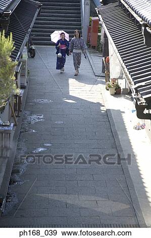 Stock Photo - Couple in traditional Japanese clothing walking down an alley, high angle view. Fotosearch