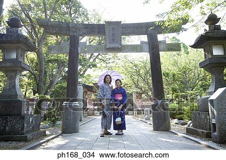 Picture - Couple in traditional Japanese clothing, standing in front of shrine. Fotosearch